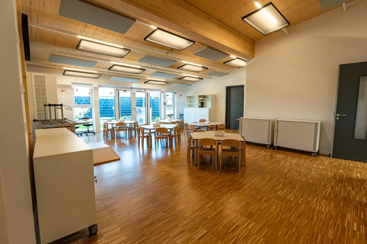Heller Essraum mit Parkettboden und Kindertischen in der Kita Schweich