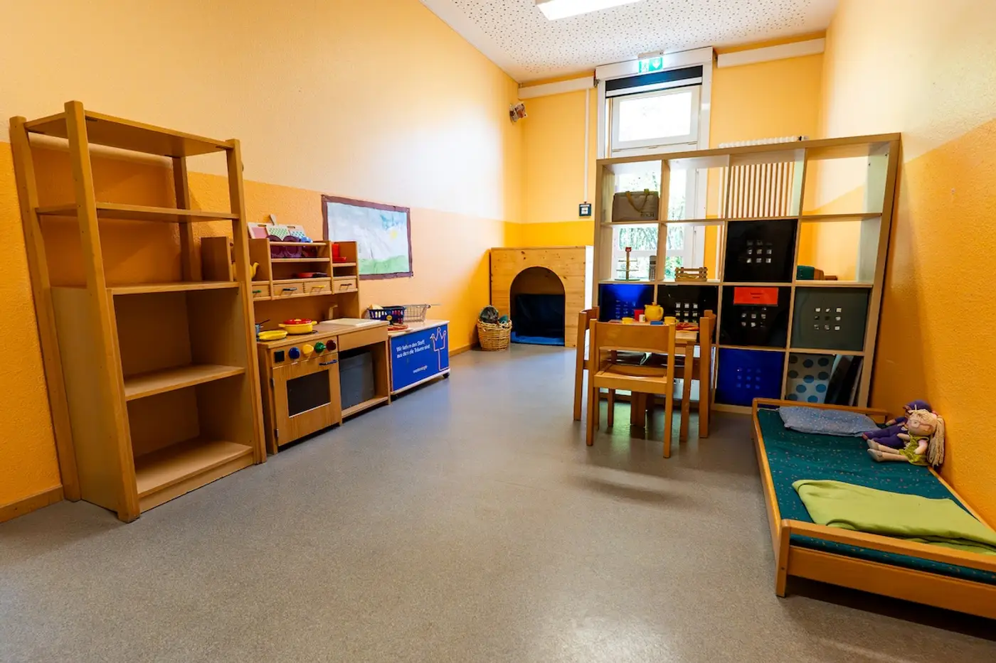 Gruppenraum der Gruppe 5 mit Spielküche, Regalen und Puppenbett in der Kita Schweich
